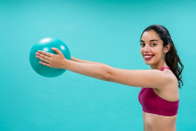 Mujer sonriente entrenando con una pelota