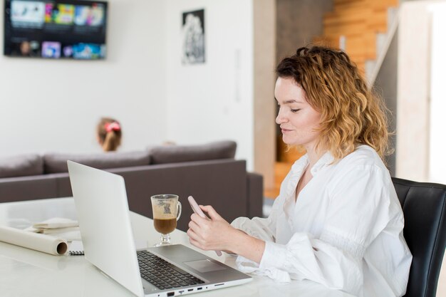 Mujer sonriente enviando mensajes de texto en casa