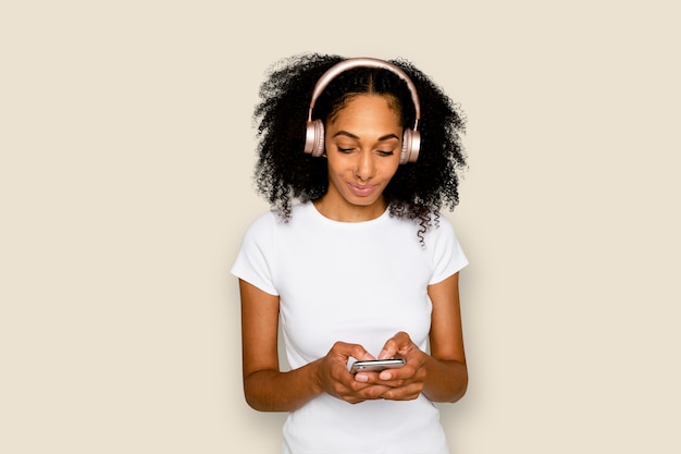 Mujer sonriente enviando mensajes de texto y escuchando música dispositivo digital