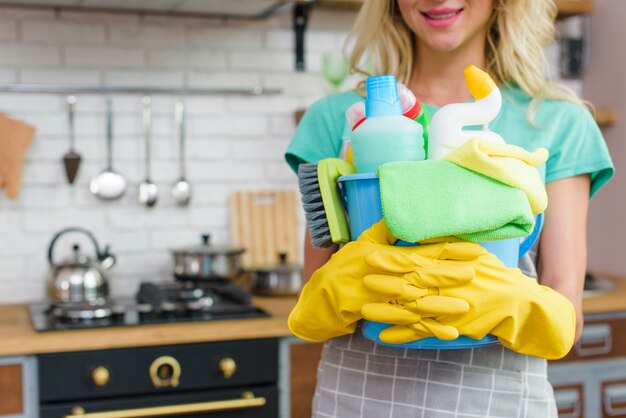 Mujer sonriente con equipo de limpieza listo para limpiar la casa