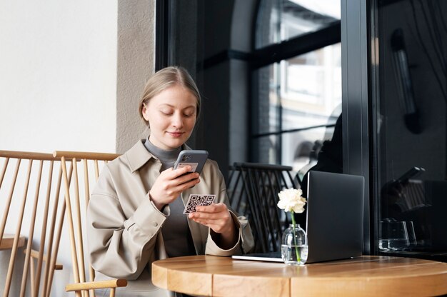 Mujer sonriente escaneando código qr en el restaurante plano medio