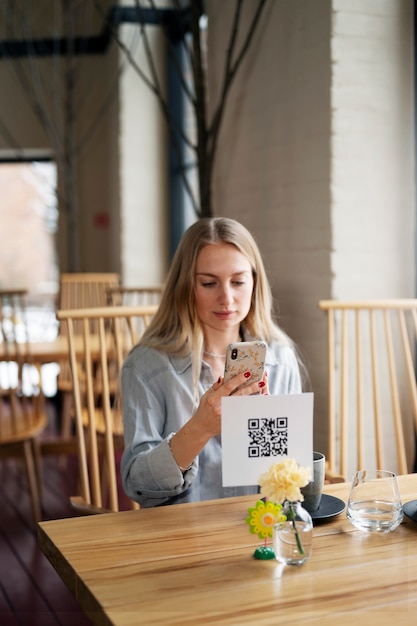 Mujer sonriente escaneando código qr en el restaurante