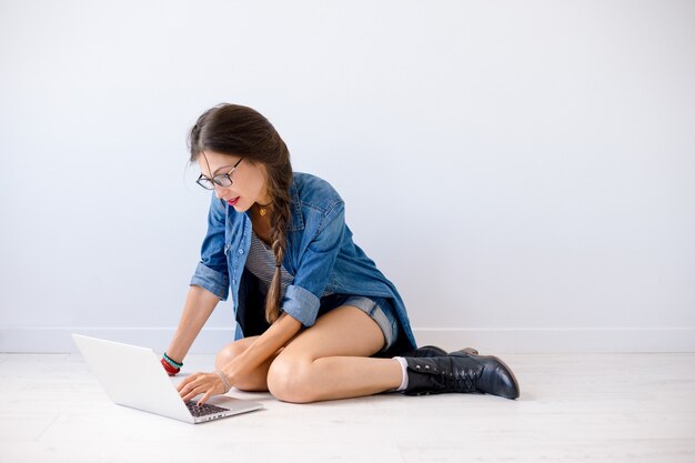 Mujer sonriente escribiendo en la computadora portátil