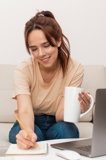 Mujer sonriente escribiendo en su cuaderno