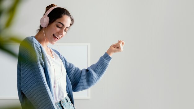 Mujer sonriente escuchando música en auriculares con espacio de copia