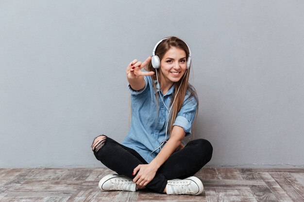 Mujer sonriente escuchando música en el piso