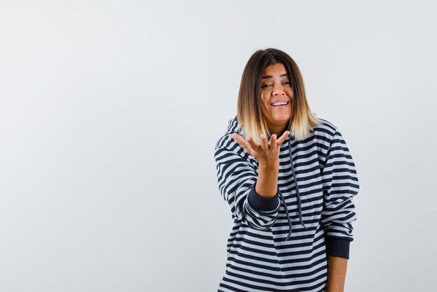 La mujer sonriente está mostrando lo que está pasando gesto con la mano sobre fondo blanco.