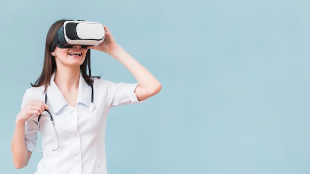 Mujer sonriente con estetoscopio con casco de realidad virtual