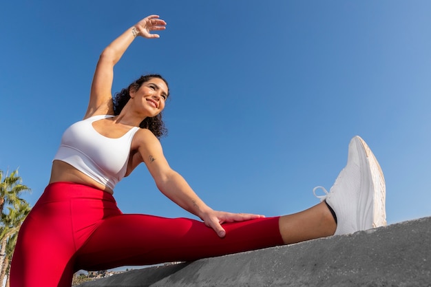 Foto gratuita mujer sonriente estirando la pierna en ángulo bajo