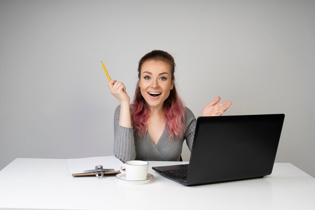 La mujer sonriente expresa sorpresa en su computadora portátil