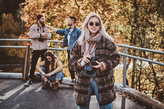 Mujer sonriente feliz con cámara de fotos está disfrutando de un brillante día de otoño en el parque.