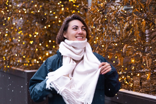 Mujer sonriente feliz caucásica disfrutando de la nieve y el invierno, vistiendo bufanda caliente