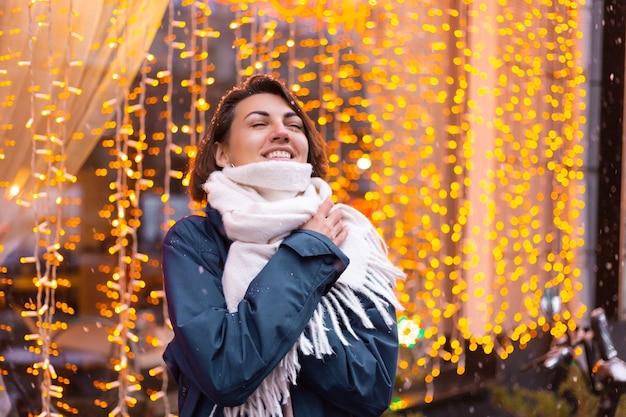 Mujer sonriente feliz caucásica disfrutando de la nieve y el invierno, vistiendo bufanda caliente