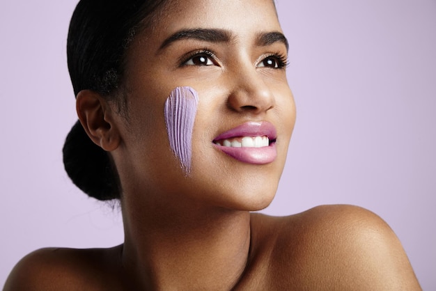 Mujer sonriente feliz con una crema en una mejilla