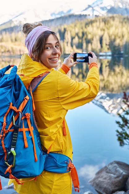 Mujer sonriente feliz en impermeable casual, lleva mochila