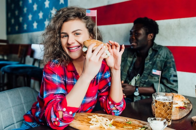 mujer sonriente feliz que tiene un descanso en el bar con el hombre en el café, hablando, riendo comer comida rápida.