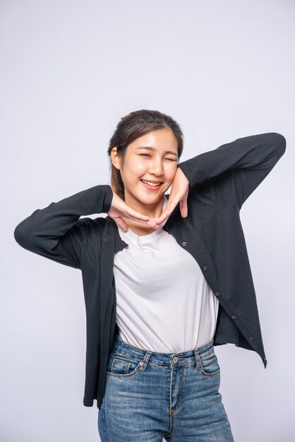 Una mujer sonriente felizmente con una camisa negra, jeans de pie, sonriendo felizmente.