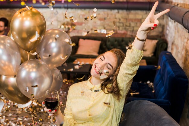 Mujer sonriente en la fiesta con copa de vino disfrutando en la fiesta