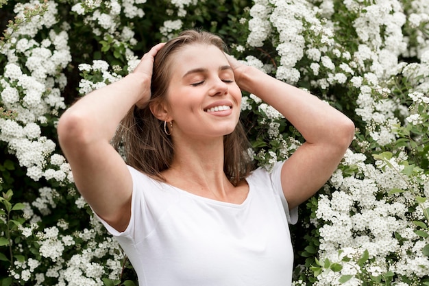 Foto gratuita mujer sonriente con flores detrás