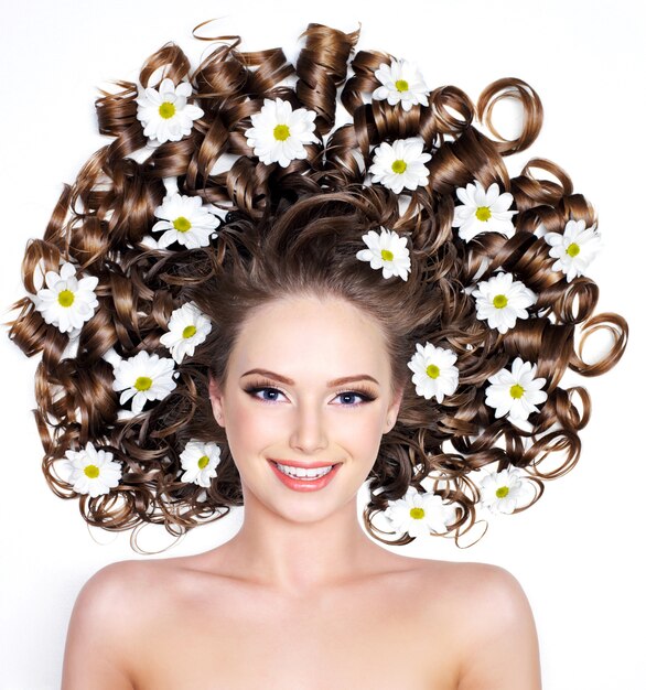 Mujer sonriente con flores en el pelo largo en blanco