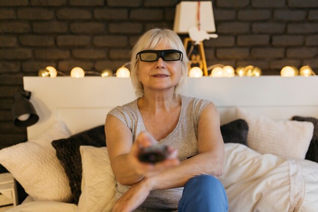 Mujer sonriente en gafas 3D viendo la televisión