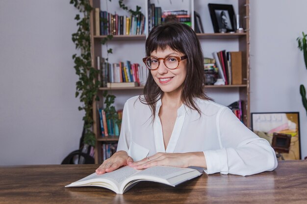 Mujer sonriente con gafas y libro abierto