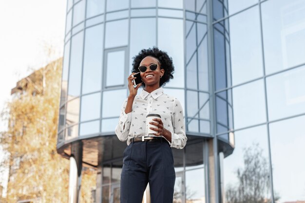 Mujer sonriente con gafas de sol hablando por teléfono