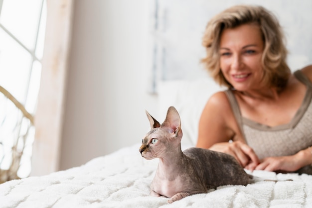 Mujer sonriente y gato en la cama de cerca