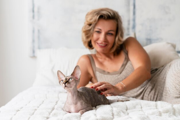 Mujer sonriente y gato en la cama tiro medio