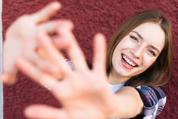 Foto gratuita mujer sonriente con gesto de parada contra la pared roja