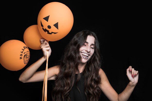 Mujer sonriente con globos de Halloween y baile
