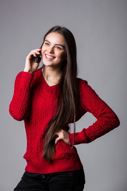 Mujer sonriente hablando por teléfono celular mirando hacia arriba en el espacio de la copia en blanco, sobre la pared blanca