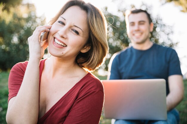 Mujer sonriente hablando por teléfono cerca del hombre