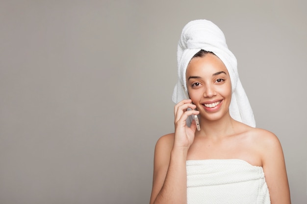 Mujer sonriente hablando por teléfono después de la ducha
