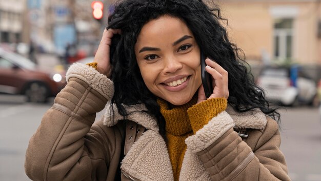 Mujer sonriente hablando por teléfono fuera