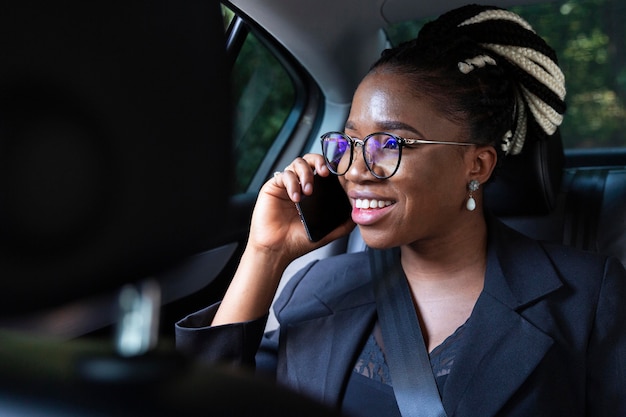 Foto gratuita mujer sonriente hablando por teléfono inteligente mientras está en su coche