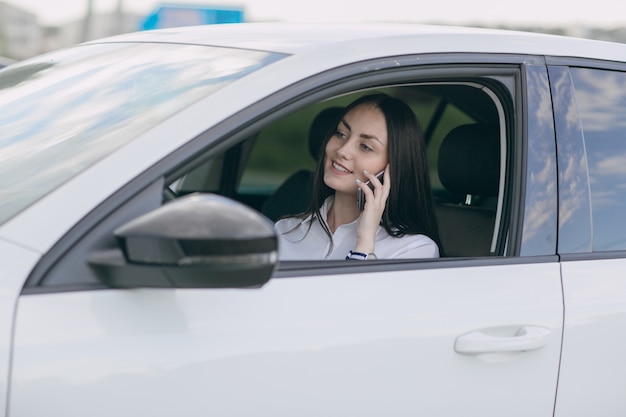 Mujer sonriente hablando por teléfono mientras conduce