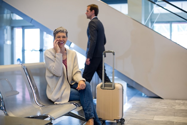 Foto gratuita mujer sonriente hablando por teléfono móvil en la sala de espera