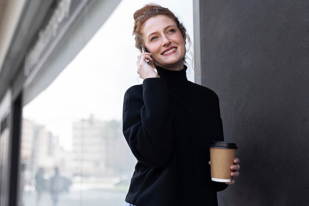 Mujer sonriente hablando por teléfono plano medio