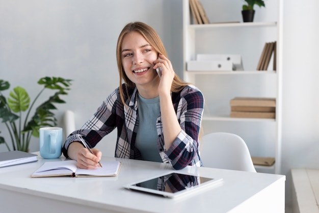 Mujer sonriente hablando por teléfono en su escritorio