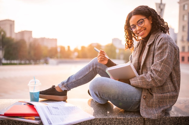 Foto gratuita mujer sonriente haciendo los deberes al aire libre