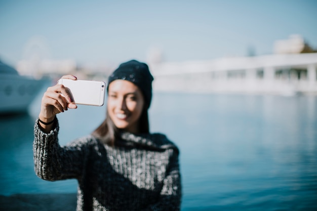 Mujer sonriente haciendo un selfie con agua en el fondo