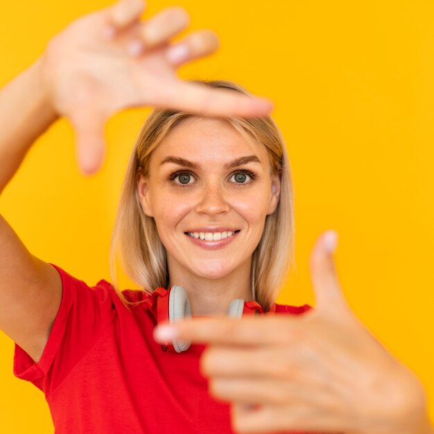 Mujer sonriente haciendo símbolo de cámara