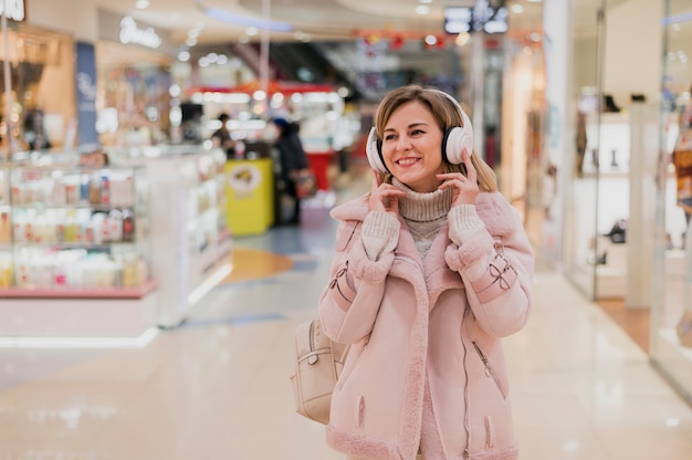 Foto gratuita mujer sonriente con heaphones en centro comercial