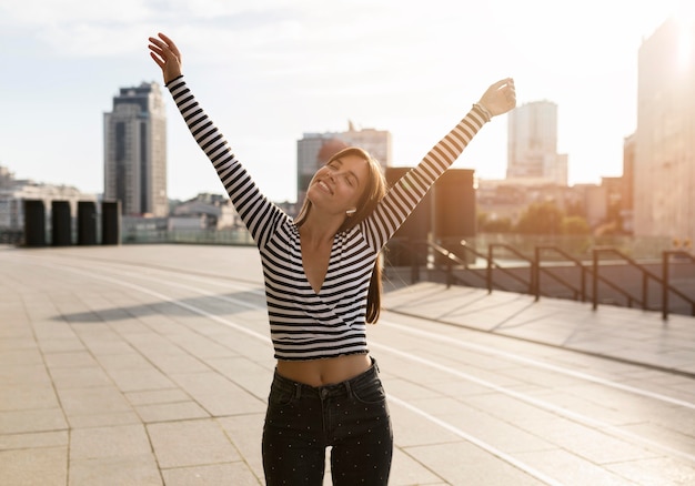 Foto gratuita mujer sonriente hermosa que presenta en luz del sol