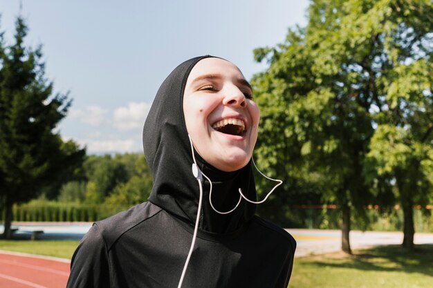 Mujer sonriente con hijab y auriculares