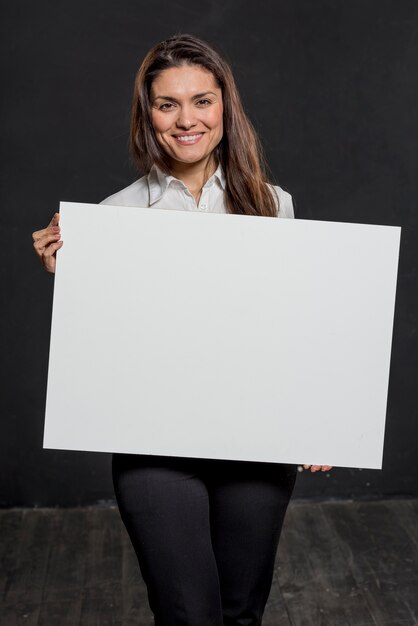 Mujer sonriente con hoja de papel en blanco