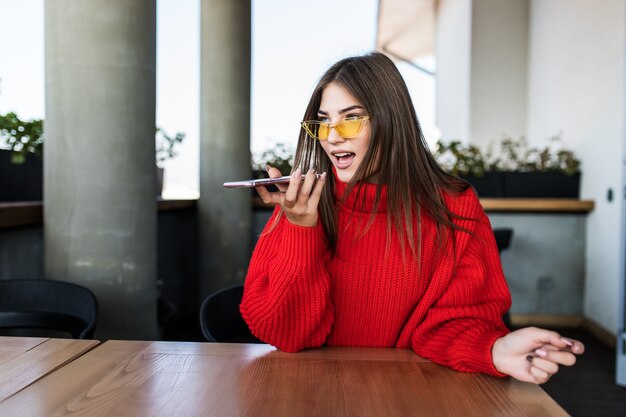 Mujer sonriente joven belleza sentada en un café y hablando por el teléfono celular