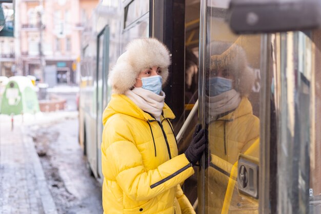 Mujer sonriente joven entra en el autobús en un día de invierno