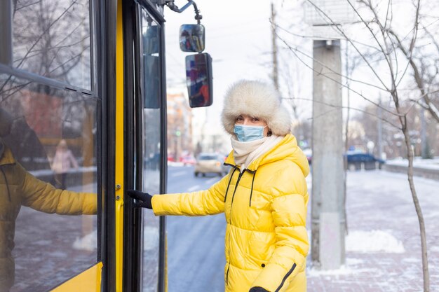 Mujer sonriente joven entra en el autobús en un día de invierno